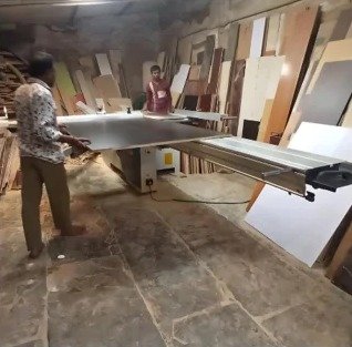 Wood work factory: workers handling boards on a cutting table
