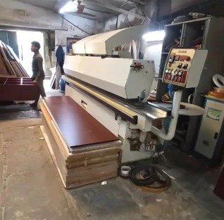 Wood work factory: edge banding machine finishing a board
